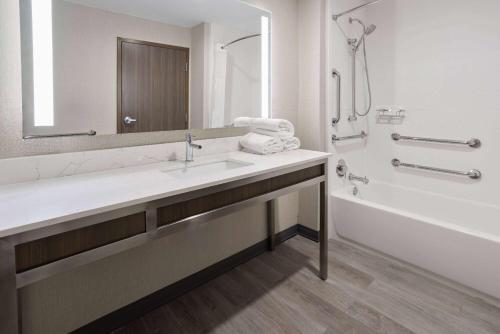 een badkamer met een wastafel, een bad en een spiegel bij La Quinta Inn & Suites by Wyndham Locust Grove in Locust Grove