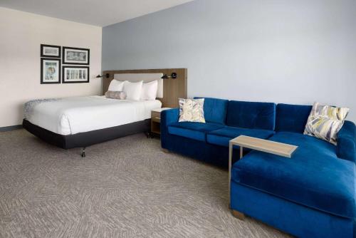 a hotel room with a blue couch and a bed at La Quinta Inn & Suites by Wyndham Locust Grove in Locust Grove