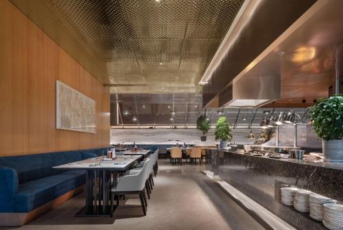 a restaurant with tables and chairs and a kitchen at Wyndham Grand Zhaoqing Downtown in Zhaoqing