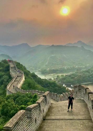 a man standing on the great wall of china at sunset at Encounter Garden Great Wall Holiday Guesthouse in Beijing