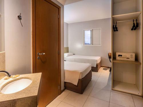 uma casa de banho com um lavatório e uma cama num quarto em ibis Styles Belém do Pará em Belém
