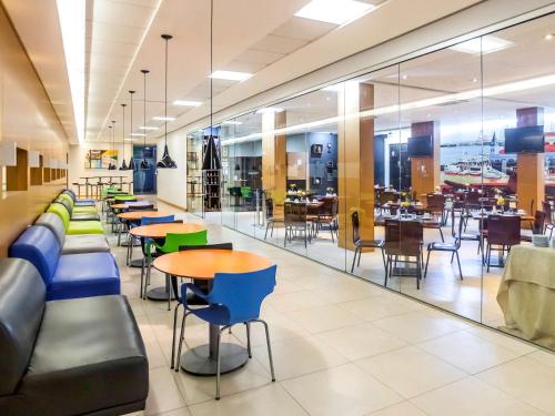 una cafetería llena de mesas y sillas y una cafetería con mesas en ibis Styles Belém do Pará, en Belém