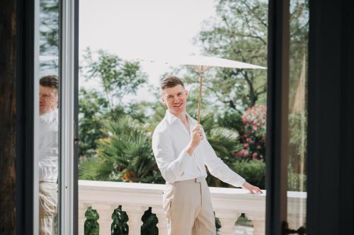 a groom holding an umbrella in front of a window at Villa De Cillis Carafa in Torre del Greco