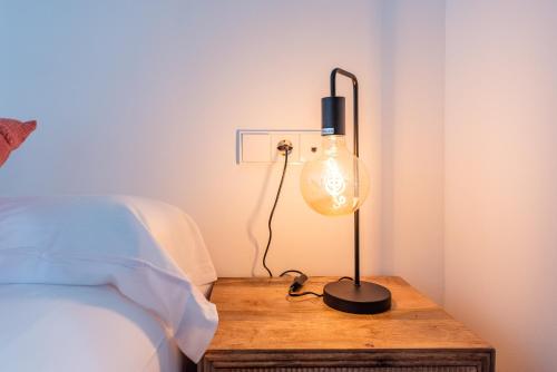 a lamp on a wooden table next to a bed at Málaga Boutique Adults Recommended in Málaga