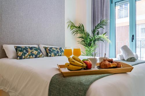 taca z owocami na łóżku z dwoma kieliszkami soku pomarańczowego w obiekcie SUNSET MALAGA - PRIME & DESIGN w Maladze