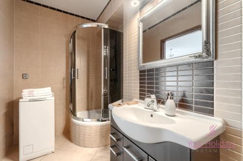 a bathroom with a sink and a shower and a mirror at Your Holidays Gryfa Pomorskiego in Międzyzdroje