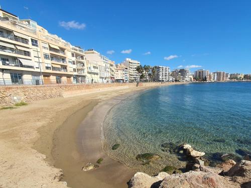 a beach with some buildings and the water at Playa de Levante, Céntrico, AC, Wifi y Parking - by Aloha Palma in Águilas