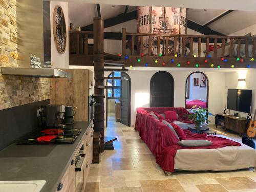un salon avec un canapé rouge dans une cuisine dans l'établissement La belle Maison d'Hôtes d'Aurélie avec SPA professionnel en pleine campagne et proche de tout, à Roquemaure
