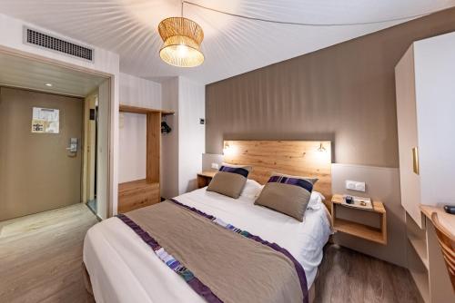 a bedroom with a large bed with a wooden headboard at Hôtel Princes de Catalogne in Collioure