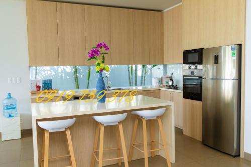 a kitchen with a counter with stools and a refrigerator at Beachfront Villa 4 Bedrooms Sanctuary Ho Tram Resort in Thuận Biên