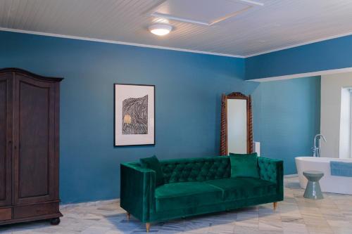 a living room with a green couch and a blue wall at Kura Botanica Hotel in Willemstad