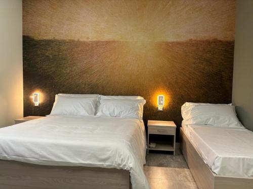 two beds in a bedroom with two lamps on the wall at Volpedo hostel in Volpedo