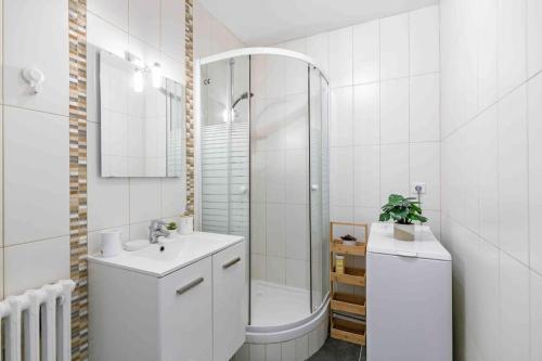 een witte badkamer met een wastafel en een douche bij Appartement avec parking et terrasse Métro 7 et Paris in Villejuif