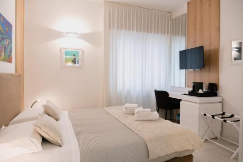 a white bedroom with a bed and a desk at Lo Studio di viale Lo Re camere & caffe’ in Lecce