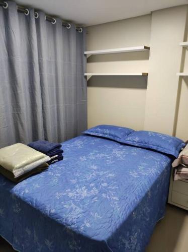 a bedroom with a bed with a blue comforter at Apartamento encantador 1 Quarto na Candangolândia in Brasilia