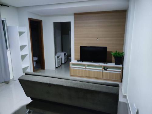 sala de estar con TV de pantalla plana en un centro de entretenimiento en Apartamento encantador 1 Quarto na Candangolândia en Brasilia
