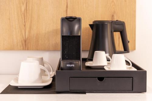 a black coffee maker and cups on a counter at Lo Studio di viale Lo Re camere & caffe’ in Lecce