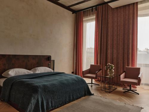 a bedroom with a large bed and two chairs at Grand Hotel in Łódź