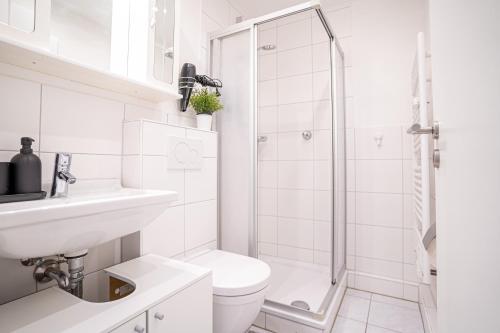 a white bathroom with a toilet and a shower at lionApartments Leverkusen in Leverkusen