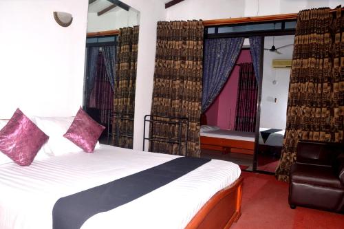 1 dormitorio con 1 cama con cortinas y silla en The Kings Villa, en Wattala