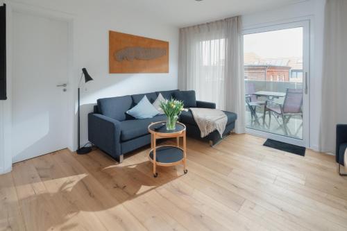 uma sala de estar com um sofá azul e uma mesa em die ELF em Norderney