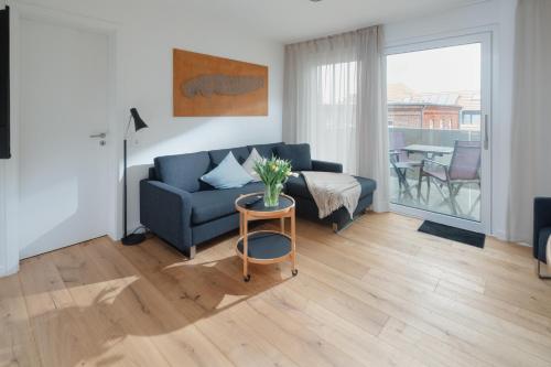 a living room with a blue couch and a table at die ELF in Norderney