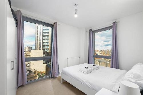 a bedroom with a white bed and a large window at Modern Serviced 3-bedroom flat in East London in London