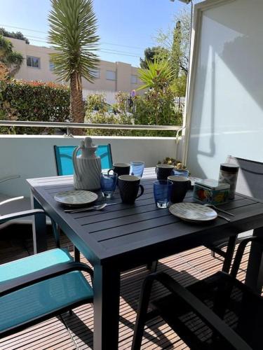 une table noire avec des assiettes et un vase sur un balcon dans l'établissement 21 - Très agréable rdc avec terrasse et parking, à Bandol