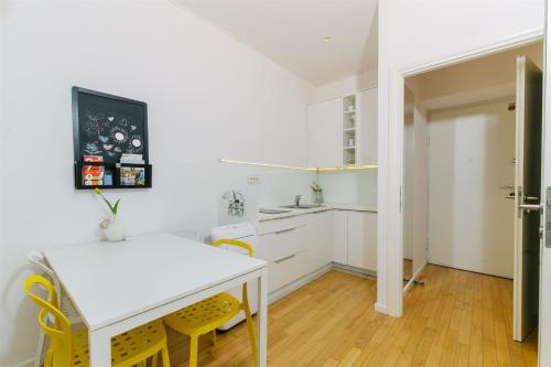 a kitchen with a white table and yellow chairs at Tia Studio in Zagreb