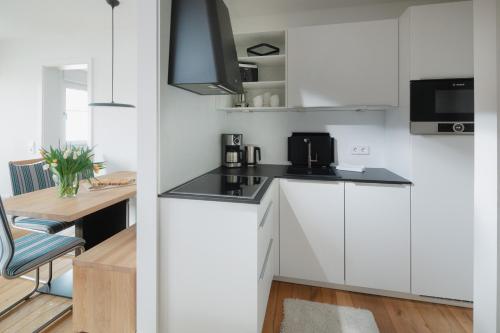 a small kitchen with white cabinets and a table at die ELF in Norderney