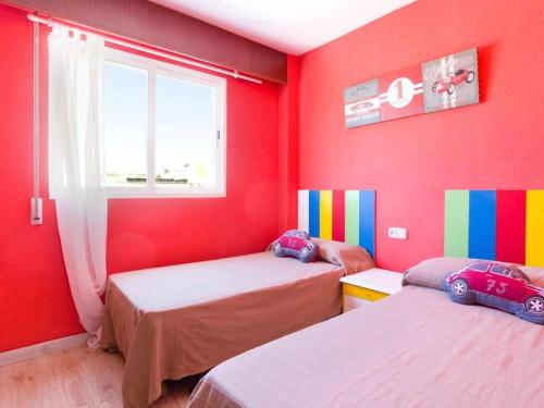 ガンディアにあるAtico con bonitas vistasの赤い壁の客室で、ベッド2台が備わります。