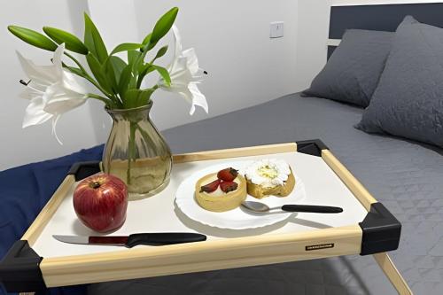 a tray with an apple and a plate of food on a bed at Flamingo Pé na Areia in Matinhos