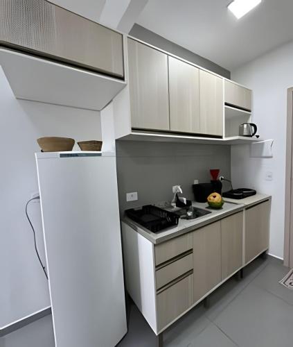 a kitchen with white cabinets and a stove top oven at Flamingo Pé na Areia in Matinhos