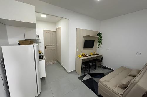 a living room with a couch and a kitchen at Flamingo Pé na Areia in Matinhos