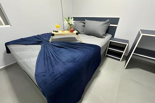 a bed with a blue blanket and a table on it at Flamingo Pé na Areia in Matinhos