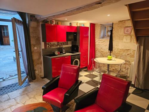 une cuisine avec des armoires rouges et une table et des chaises dans l'établissement LA GRANGE DE LA VALLÉE DU CHER, à Chissay-en-Touraine