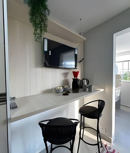 a kitchen with two black stools and a counter at Flamingo Pé na Areia in Matinhos