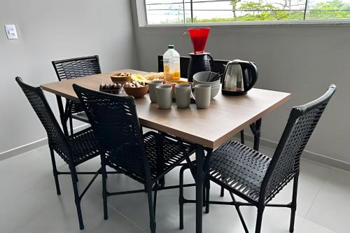 a wooden table with chairs and food on it at Flamingo Pé na Areia in Matinhos