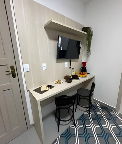 a room with a desk with chairs and a computer monitor at Flamingo Pé na Areia in Matinhos