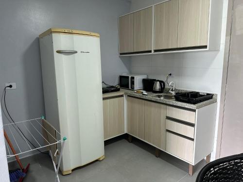 a small kitchen with a refrigerator and a microwave at Flamingo Pé na Areia in Matinhos