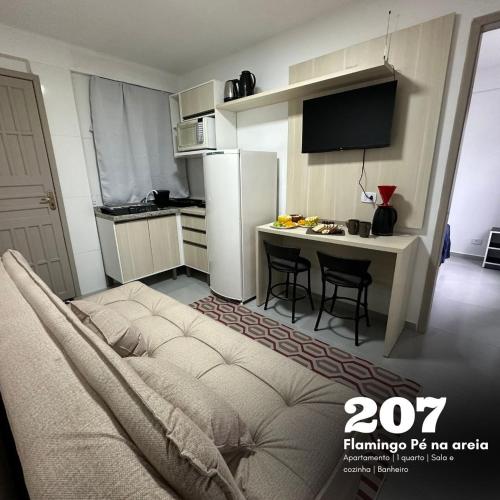 a small kitchen with a table and a refrigerator at Flamingo Pé na Areia in Matinhos
