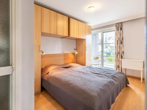 Un dormitorio con una cama grande y una ventana en Parnasse with a central location, en Koksijde
