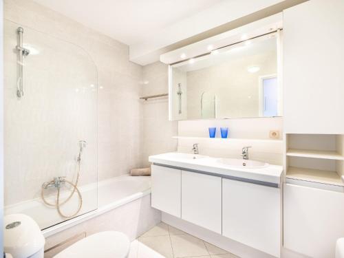 y baño blanco con bañera, lavamanos y ducha. en Parnasse with a central location, en Koksijde