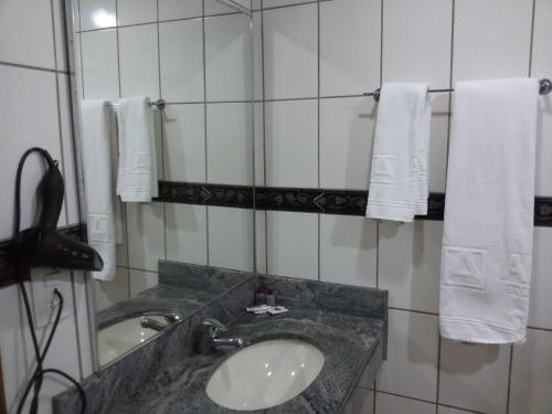 a bathroom with a sink and a mirror and towels at Airam Brasília Hotel in Brasilia