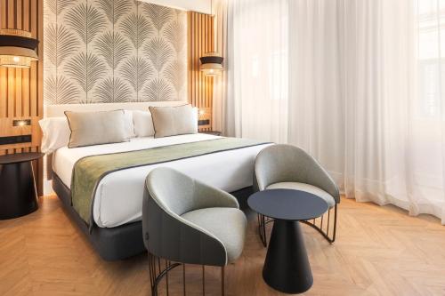 - une chambre avec un grand lit et une chaise dans l'établissement Catalonia Atocha, à Madrid