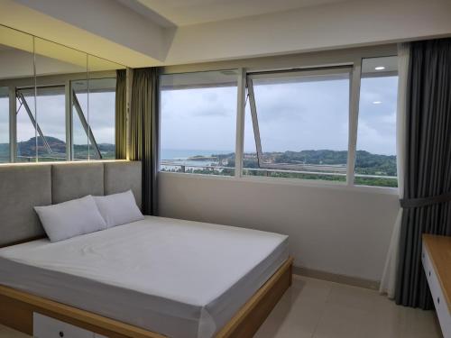 a bedroom with a bed and windows with a view at THE NOVE NUVASA KALANI TOWER in Nongsa