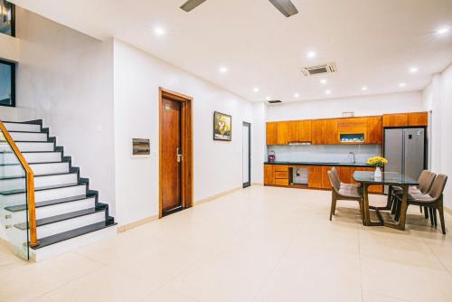 a living room with a staircase and a table and chairs at Biệt Thự Villa - Sao Biển - Ngọc Trai FLC Sầm Sơn in Sầm Sơn