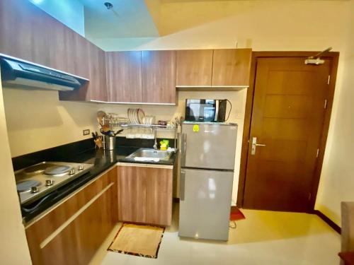 a small kitchen with wooden cabinets and a refrigerator at 1bedroom Condo For rent with WiFi pool and gym in Cebu City