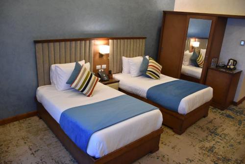 a hotel room with two beds and a mirror at Golden Jewel Ismailia Resort in Ismailia