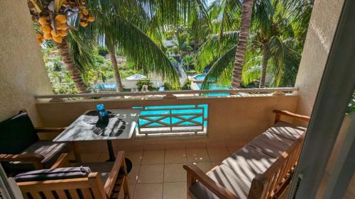 balkon ze stołem, krzesłami i palmami w obiekcie Charming apartment close to beach & amenities - Appartement de charme proche plage w mieście Flic-en-Flac